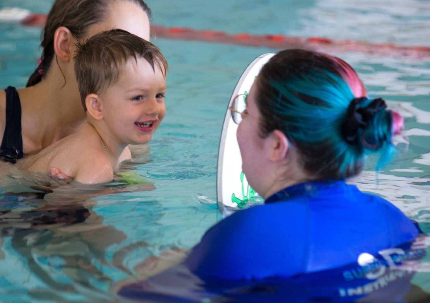 Baby smiling at teacher in swimming lesson