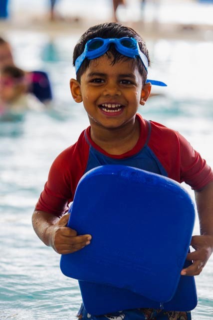 Boy smiling standing holding kickboard