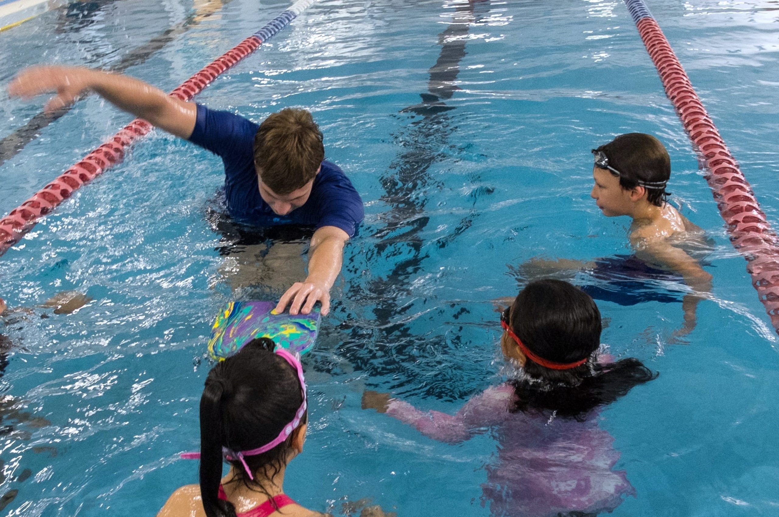 Teacher visually demonstrating freestyle to swimming class