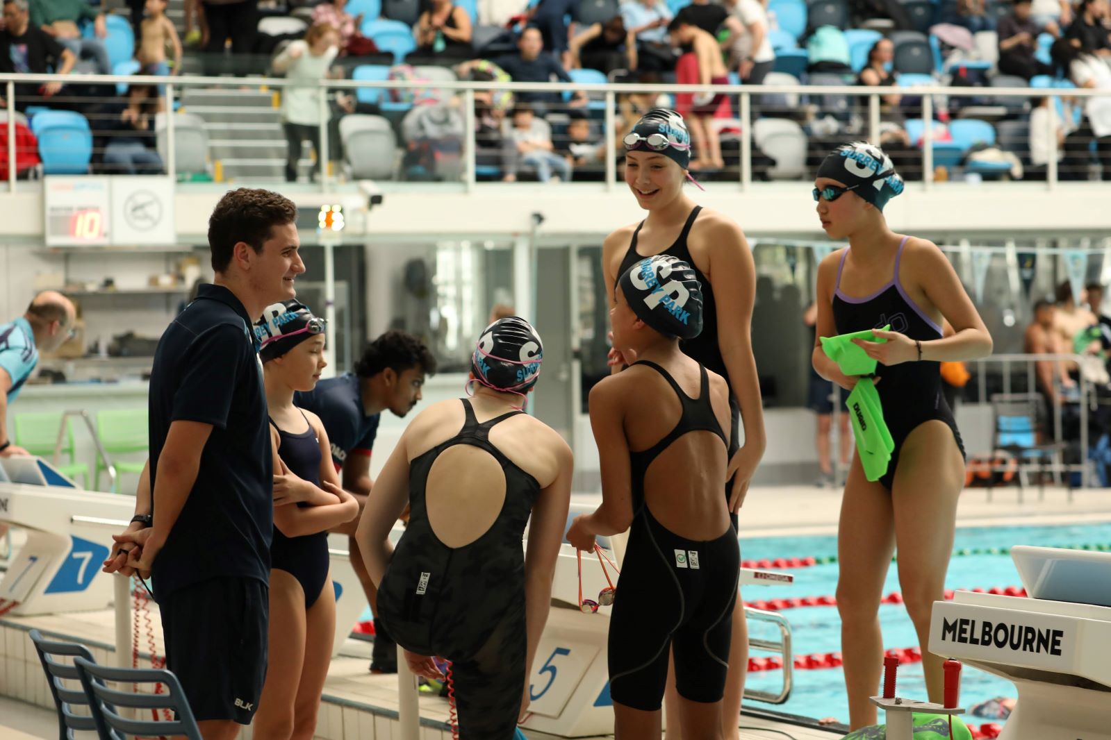 Junior coach and female swimmers relay team laughing after a race
