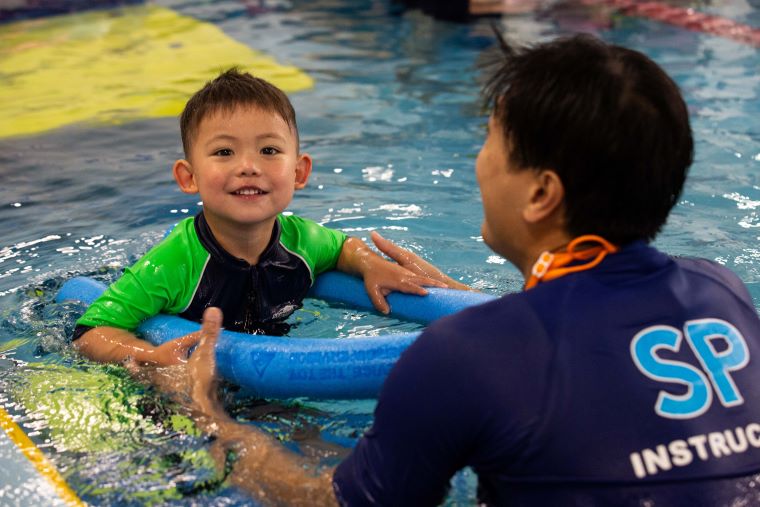 Boy holding noodle speedboat smiling